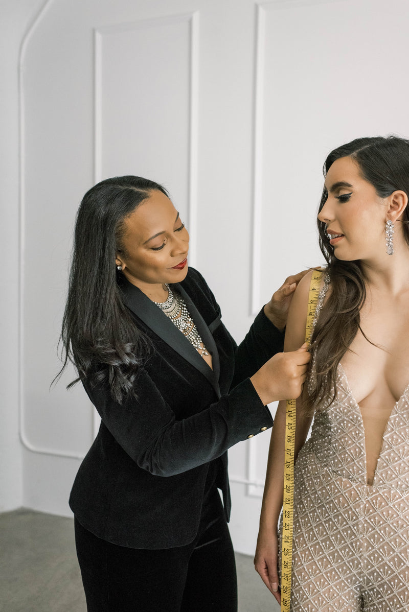 Designer and bride at fitting making sure sleek beaded wedding jumpsuit fits perfectly