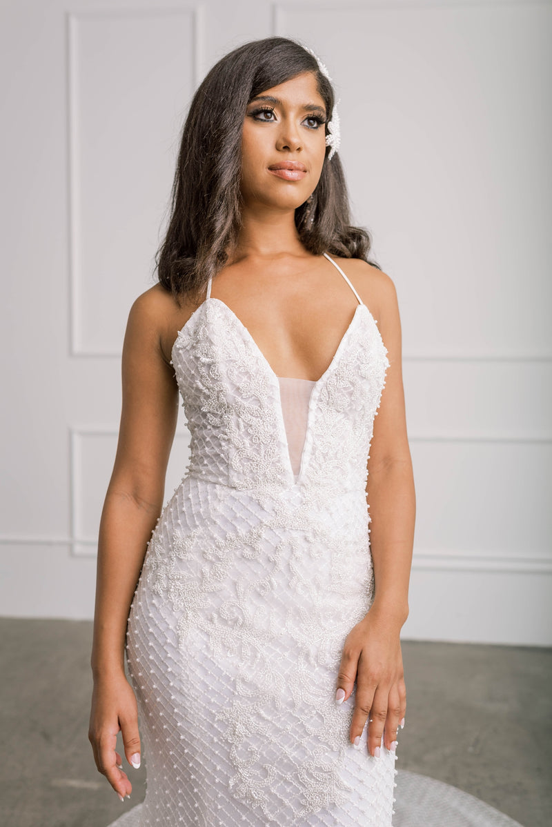 Bride trying on wedding dress with hand-appliqued pearl embroidered lattice lace with statement beading