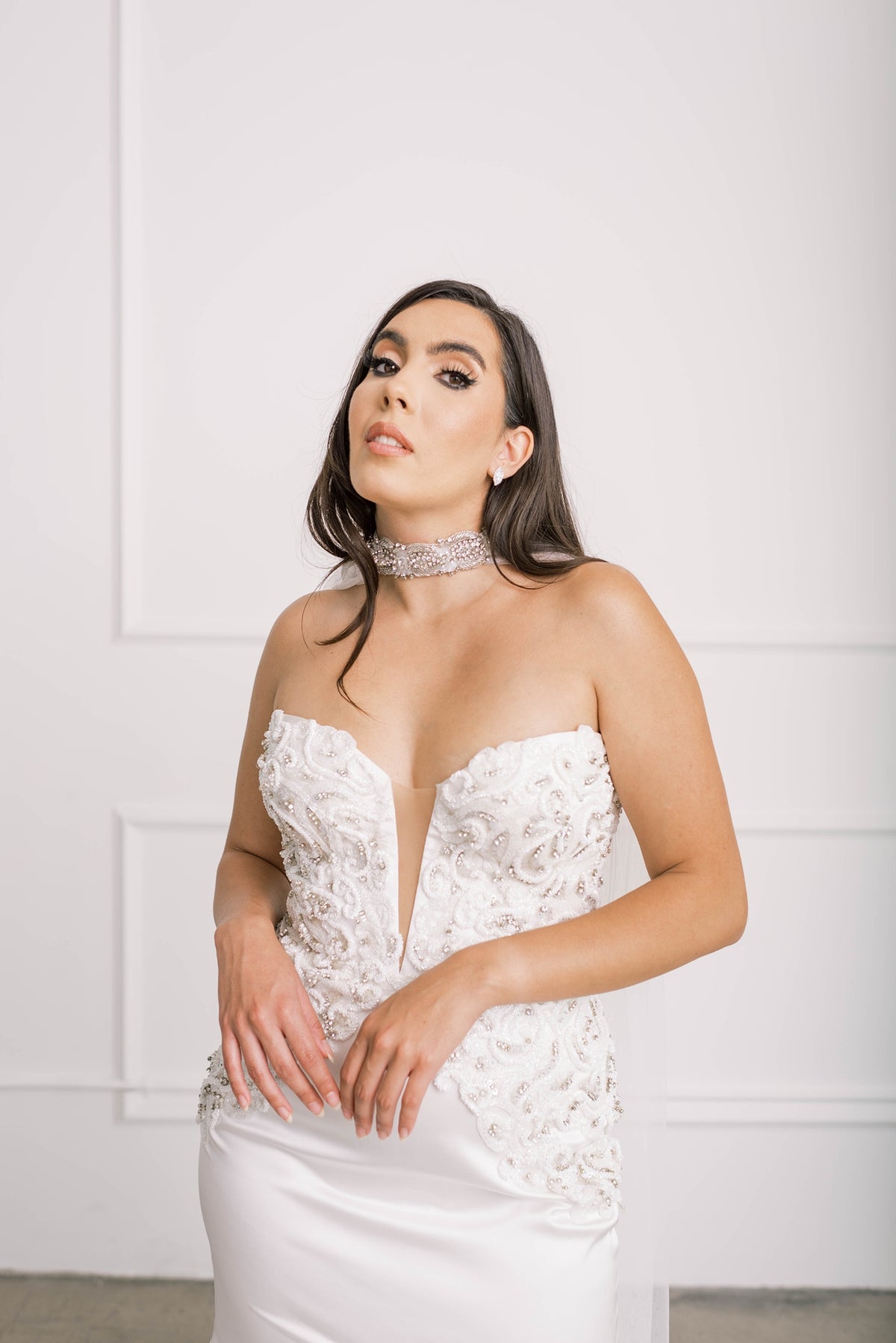 Timeless bride trying on off-white wedding dress and statement choker cape