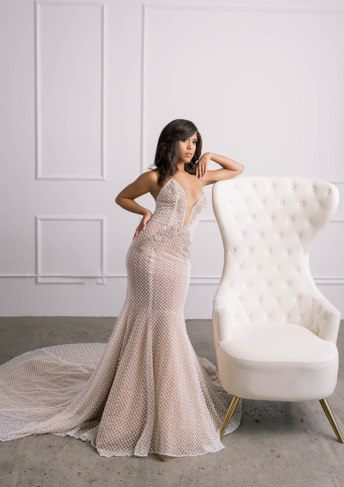 Bride leaning on chair wearing embroidered wedding dress with and statement Swarovski crystal and pearl beading