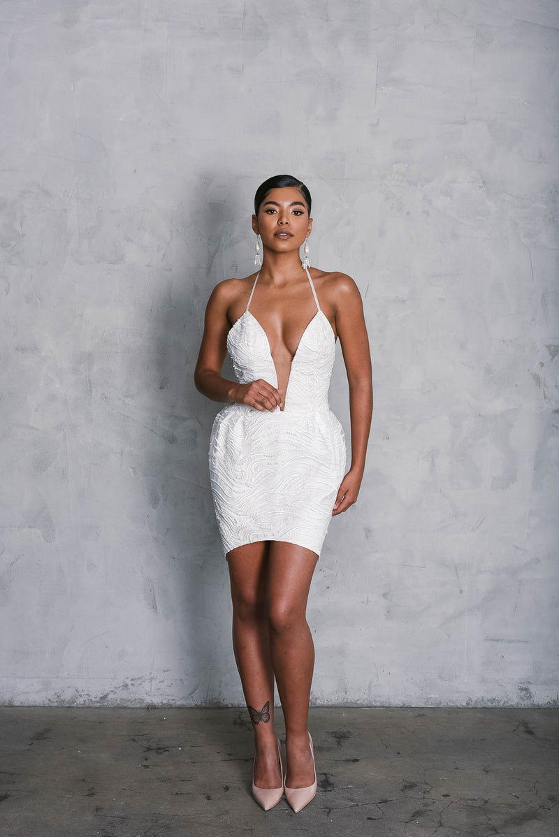 Fashion forward bride in a daring short wedding dress with plunging neckline and impeccable fit