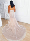 Back view of bride trying on trumpet fit and flare wedding dress with long train